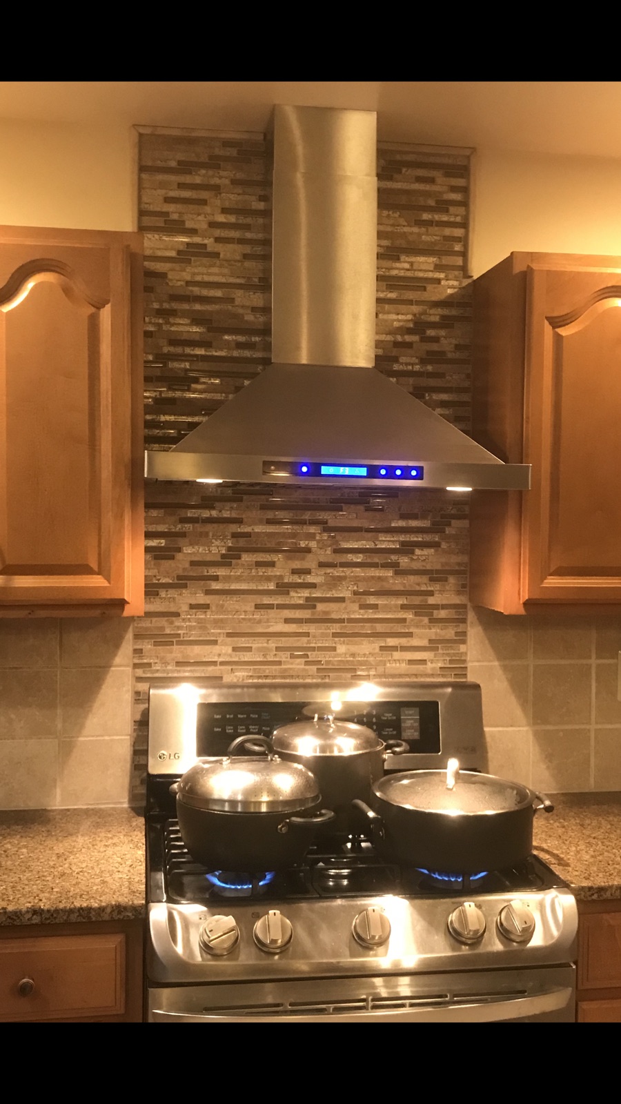 Kitchen with stainless steel island range hood and tile backsplash